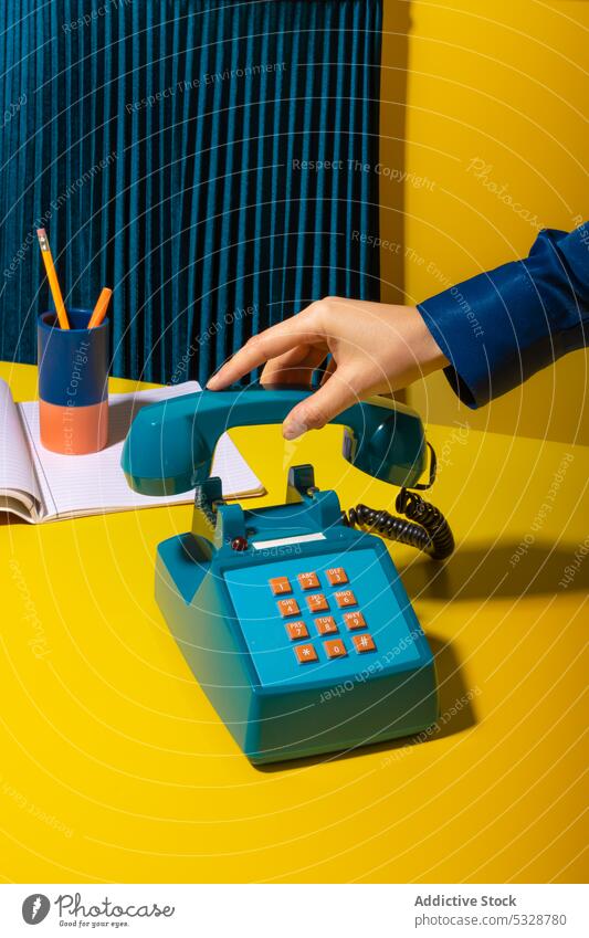 Person, die das Telefon auflegt, in der Nähe von Büromaterial aufhängen Mobilteil retro ruhend Notebook Planer Vorrat altmodisch altehrwürdig kreativ