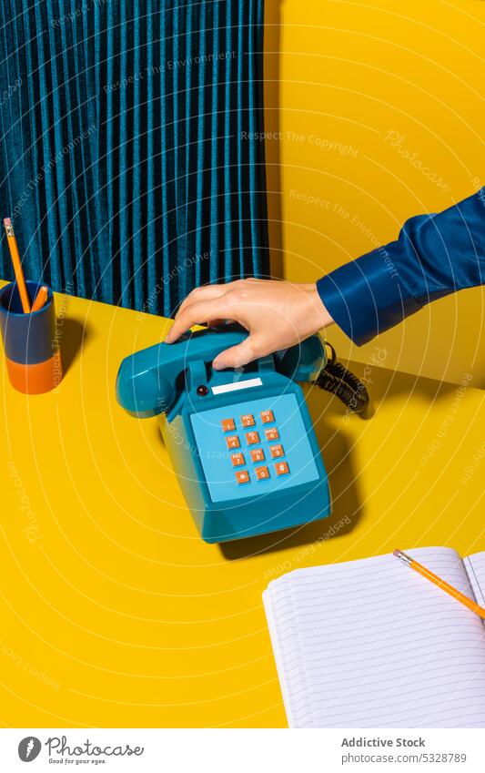 Person, die das Telefon auflegt, in der Nähe von Büromaterial aufhängen Mobilteil retro ruhend Notebook Planer Vorrat altmodisch altehrwürdig kreativ