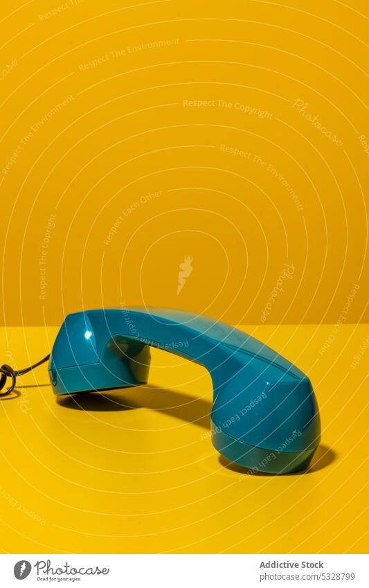 Hörer eines Retro-Telefons auf einem gelben Schreibtisch Mobilteil retro ruhend Telefonanruf Anruf Kontakt Kommunizieren Kabel Schnur Draht altmodisch