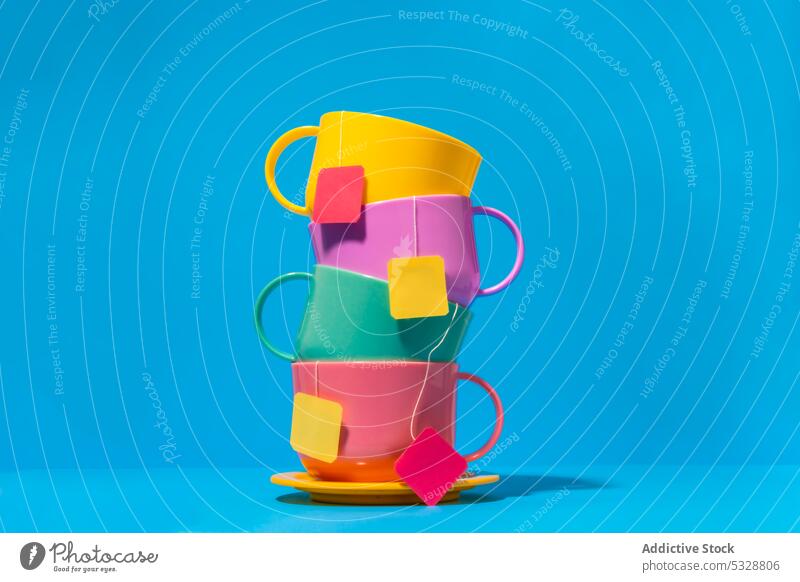 Bunte Tassen mit Teebeuteln auf blauem Hintergrund Untertasse Keramik trinken Getränk farbenfroh Teetrinken hell Porzellan Zusammensetzung Design Kulisse Becher