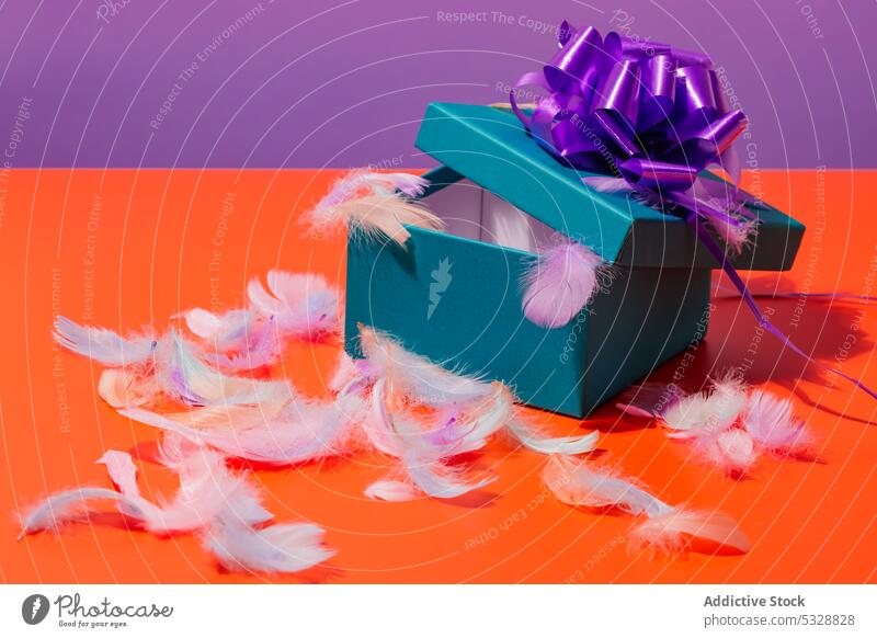 Geöffnete Geschenkbox mit Federn auf dem Tisch Kasten farbenfroh präsentieren Überraschung Schleife hell lebhaft feiern festlich Schachtel Paket Design