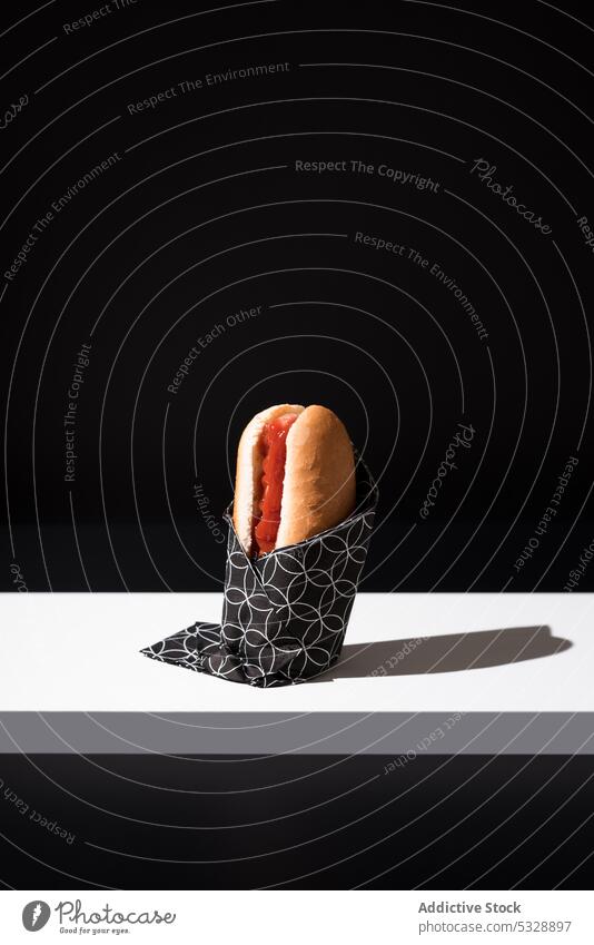 Appetitlicher Hot Dog auf Serviette über schwarzem Tisch Hotdog lecker Fastfood organisch frisch sehr wenige Kontrast Wurstwaren Ketchup Lebensmittel süß