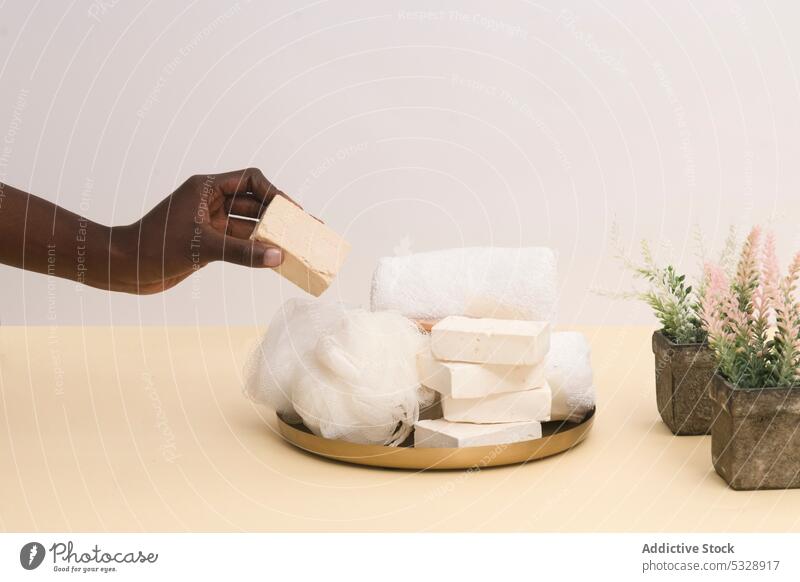 Crop-Person nimmt Seifenstück auf Teller Frau Bar Hand Pflanze Hygiene Tisch organisch natürlich Hautpflege nehmen Produkt frisch Wellness duftig Attrappe