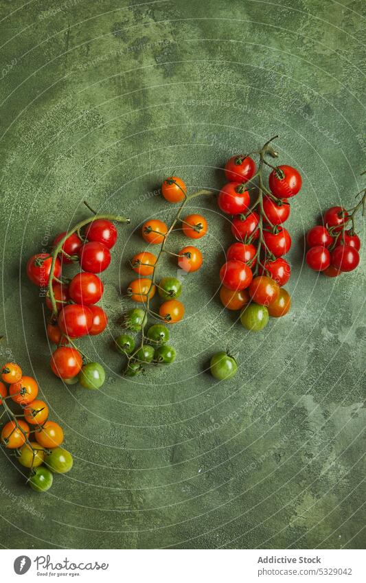 Verschiedene frische Kirschtomaten auf grüner Oberfläche Kirsche Tomate unreif Haufen roh natürlich organisch Gemüse Ernte Lebensmittel Gesundheit geschmackvoll