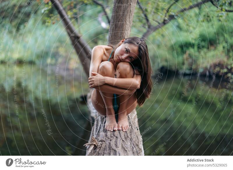Ruhige Frau umarmt Knie auf Baumstamm See Wälder Wald Sommer Kofferraum Urlaub Natur sich[Akk] entspannen Wasser Knie umarmend jung Feiertag Bikini Teich ruhen