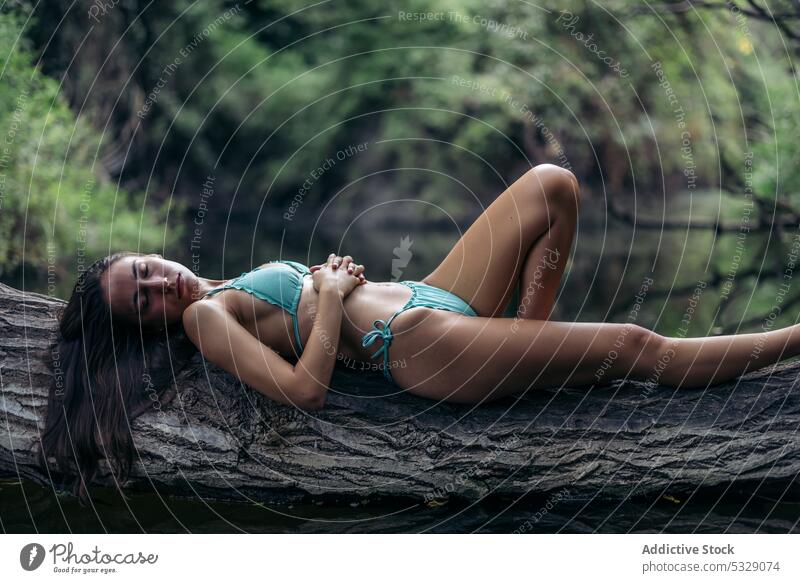 Schlanke Frau im Bikini auf Baumstamm liegend See ruhen Kofferraum Natur verträumt träumen Badeanzug Badebekleidung jung Sommer passen Wasser Gelassenheit