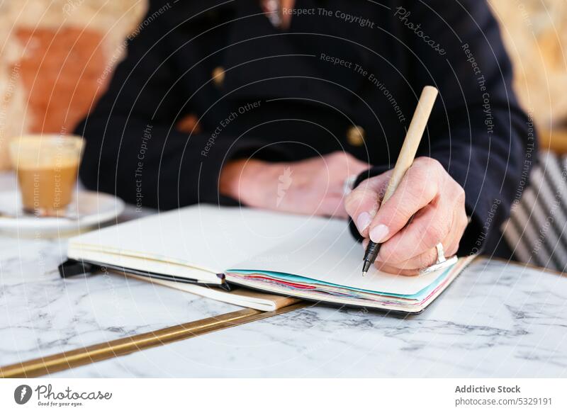 Frau mit Notizbuch am Tisch sitzend schreiben zur Kenntnis nehmen Café Planer Notebook Hinweis Kaffee Tasse Arbeit Straße Lebensmitte reif Getränk Heißgetränk