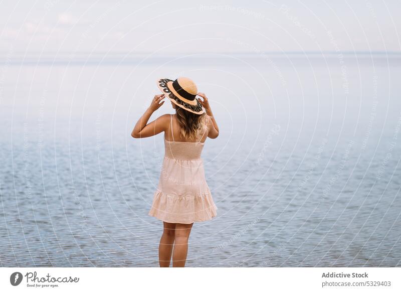 Frau mit Sonnenhut bewundert Meereslandschaft Tourist bewundern Ufer sich[Akk] entspannen Kälte wolkig Model Hut reisen Ausflug Reise erkunden Sommer Urlaub