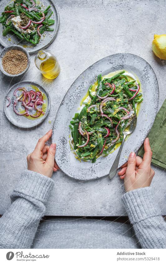 Unbekannte Person mit Teller mit appetitlichem Salat Salatbeilage Vegetarier Zwiebel Kraut Gemüse Tisch Bestandteil Lebensmittel Speise frisch Portion organisch