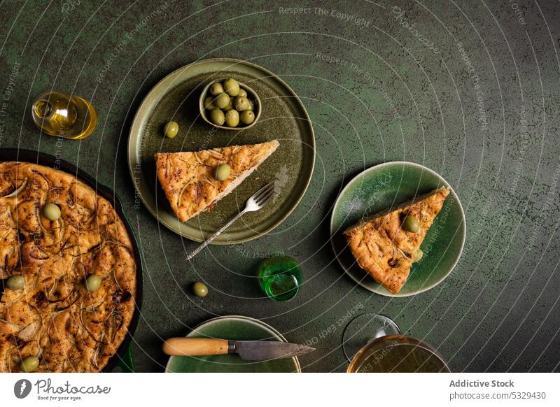 Leckeres Focaccia-Brot mit grünen Oliven auf einem Teller serviert Gabel Messer gebacken Lebensmittel Spielfigur Tradition oliv Ernährung Tisch Ofen Italienisch
