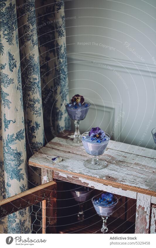 Kristallgläser mit leckerem Pudding im Schrank süß Dessert blaue Spirulina Kulisse Blume Kabinett sortiert Veganer Leckerbissen Dekor geschmackvoll