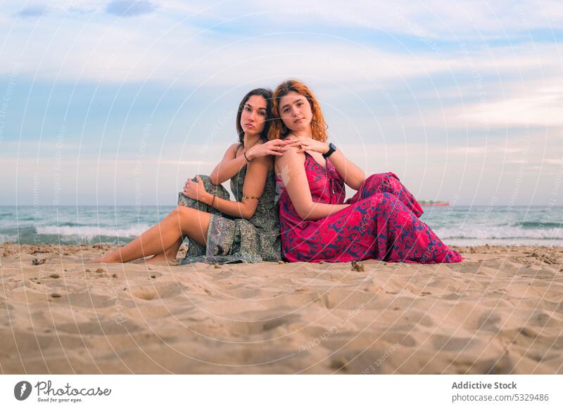 Zusammensitzende Frauen am Meeresufer Freund Freundschaft Zusammensein Strand MEER Sommer Sand Urlaub Rücken an Rücken Sonnenuntergang Küste besinnlich