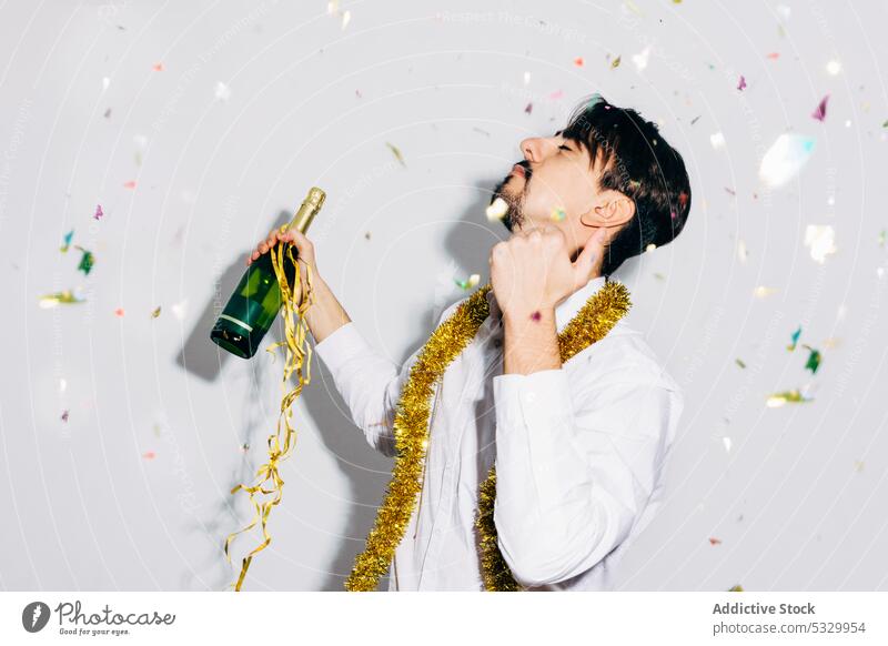 Betrunkener bärtiger Mann mit einer Flasche Champagner während der Weihnachtsferien Party Weihnachten betrunken Mikrofon feiern Konfetti Porträt festlich