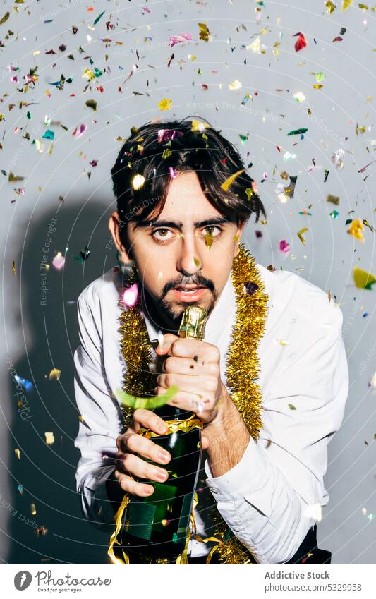 Betrunkener bärtiger Mann mit einer Flasche Champagner während der Weihnachtsferien Party Weihnachten betrunken Mikrofon feiern Konfetti Porträt festlich