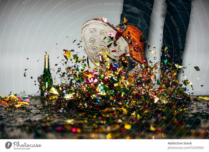 Gesichtsloser Mann in eleganten Stiefeln, der während einer Party einen Haufen Konfetti kickt Kick festlich feiern Feiertag stylisch Champagne mehrfarbig Stil