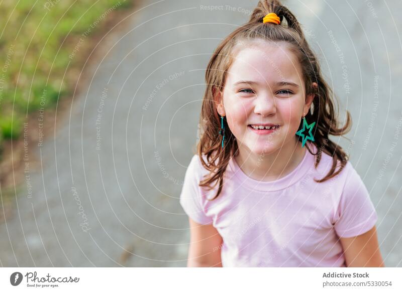 Glückliches kleines Mädchen mit Pferdeschwanz Haar auf der Straße Lächeln Porträt heiter Kind Kindheit Asphalt angenehm positiv froh herzlich charmant Freude