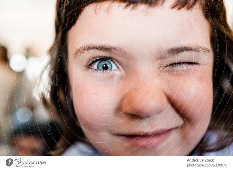 Nettes Mädchen zwinkert der Kamera auf unscharfem Hintergrund zu Zwinkern Lächeln Porträt spielerisch lustig Kind Kindheit heiter Glück niedlich Vorschule