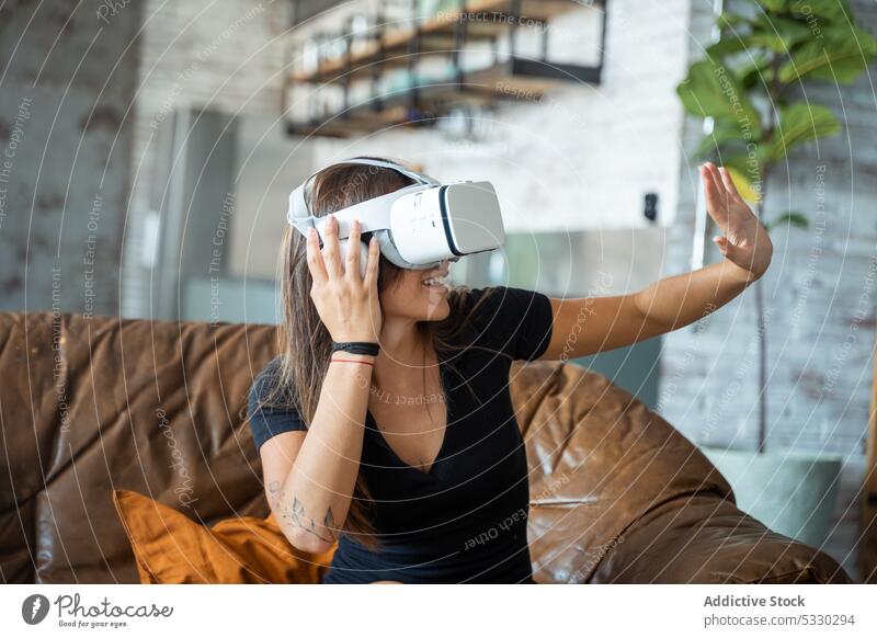 Frau in VR-Headset interagiert mit digitaler Welt Videospiel interagieren spielen Virtuelle Realität Sofa heimwärts Erfahrung Apparatur Gerät Wohnzimmer