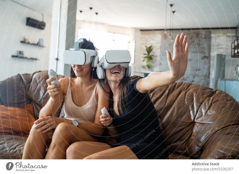 Aufgeregte Frauen in VR-Headsets spielen zu Hause ein Videospiel aufgeregt Schutzbrille Freund Spaß Virtuelle Realität Erfahrung heiter unterhalten interagieren