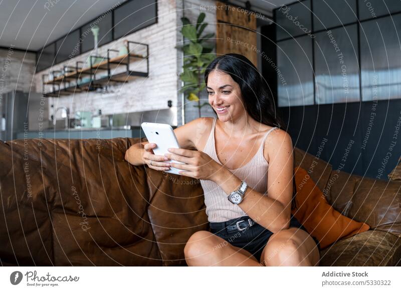 Lächelnde junge Frau mit Tablet auf dem Sofa Smartphone Tablette heimwärts heiter gemütlich Liege Wohnzimmer Apparatur Gerät ruhen lässig online Mobile Internet