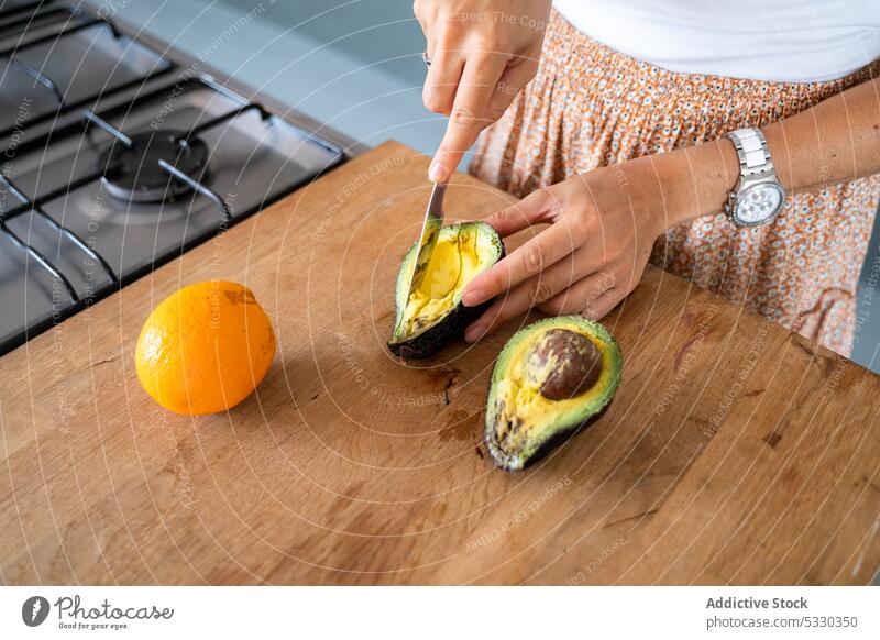 Crop-Frau schält Avocado, während sie ein leckeres Frühstück zubereitet sich[Akk] schälen Zuprosten Croissant empanada Messer Schneidebrett vorbereiten