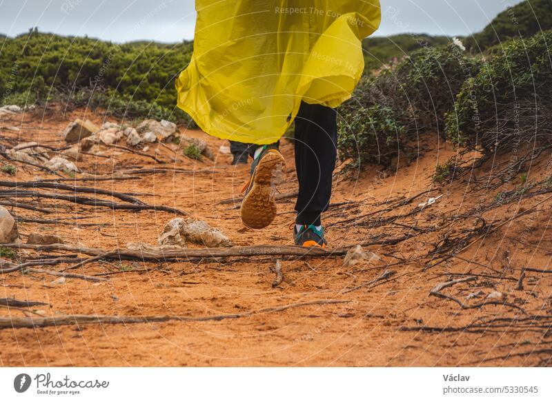 Wanderung auf dem Fischerpfad im Süden Portugals bei regnerischem Wetter in Richtung Kap St. Vicente. Raue Landschaft Regenmantel Person schützend Weg