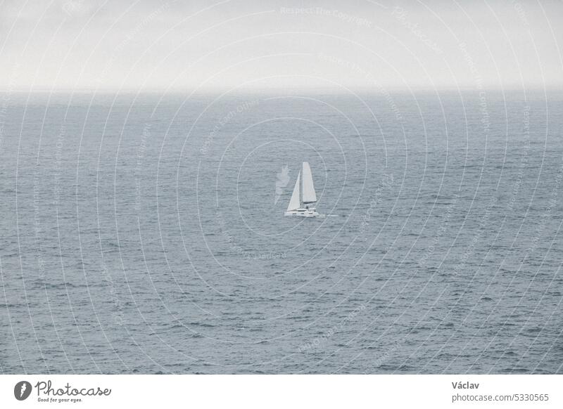 Weißer Segelfisch segelt durch den stürmischen Atlantik bei regnerischem Wetter im Süden Portugals Segelboot Sport Verkehr winken Schiff Wind Jacht Meer
