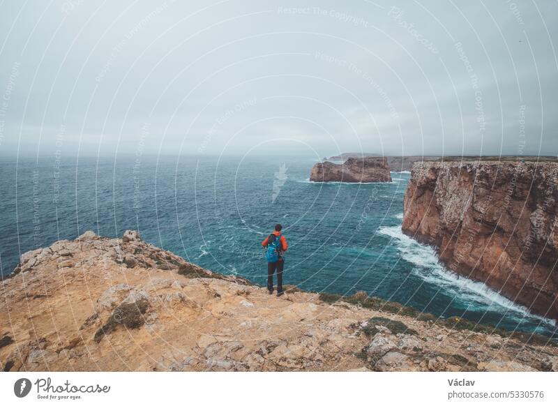 Der schwarzhaarige Abenteurer steht am Ende des Kaps Cabo de Sao Vicente im Südwesten Portugals in der Region Algarve. Der Mann genießt seine Freiheit. Wanderung des Fisherman Trail