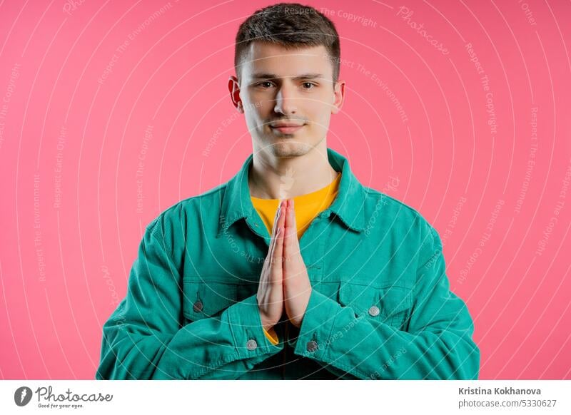 Junger Mann betet, bittet auf rosa Hintergrund. Hoffnungsvolles Gebet bittet um Hilfe bei beten Hände Glaube Gott Hilfsbereitschaft Religion jung Erwachsener