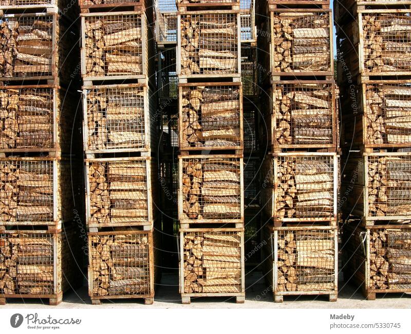 Sorgfältig gestapelte quadratische Behälter mit Brennholz im Sonnenschein auf einer Freifläche mit Lagerplatz in Schloß Holte-Stukenbrock bei Gütersloh in Ostwestfalen-Lippe