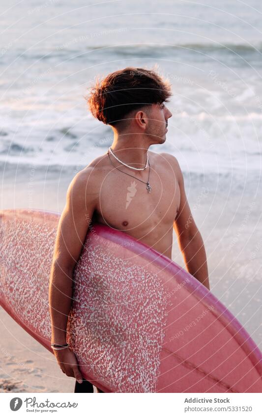 Entfernter Surfer auf sandigem Küstenstreifen Mann Strand Surfbrett Sonnenuntergang MEER Urlaub Sommer winken Feiertag männlich Meer ohne Hemd Ufer Sand Wasser