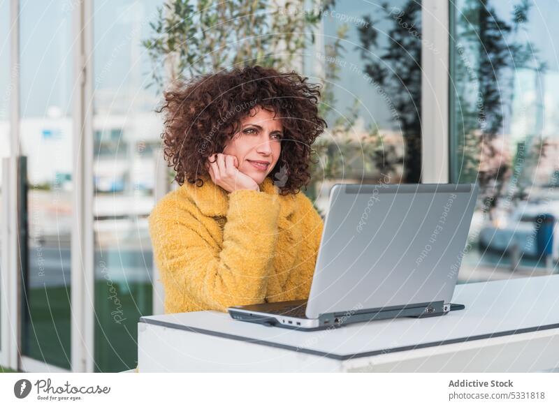 Frau tippt auf einem Laptop in einem Straßencafé Café benutzend Arbeit freiberuflich Lächeln abgelegen Tippen Terrasse Glück Browsen Apparatur Gerät Projekt