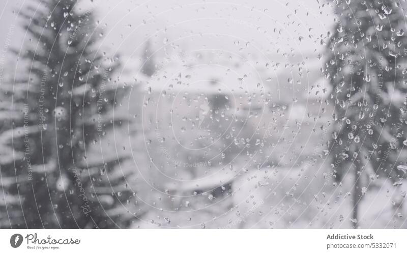 Glas mit Regentropfen gegen unscharfe verschneite Straße im Winter Stadt Fenster kondensieren Tropfen durchsichtig Tröpfchen Schnee Glasscheibe nass winterlich