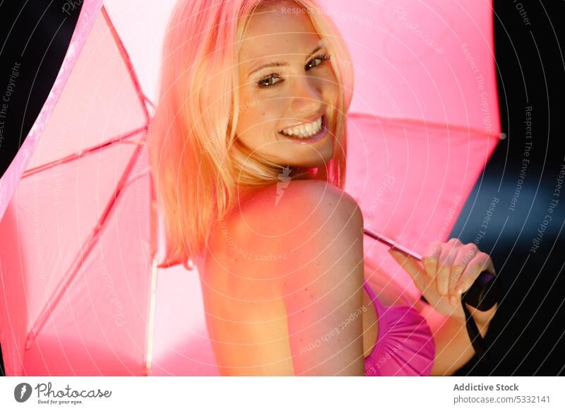 Fröhliche Frau mit rosa Regenschirm Lächeln sich[Akk] entspannen schön attraktiv heiter aufgeregt Natur Model Badeanzug Badebekleidung sinnlich freundlich BH