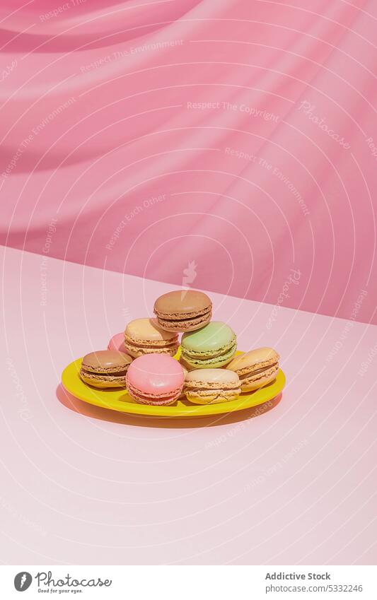 Bunte Makronen auf rundem Teller vor rosa Hintergrund Dessert süß lecker geschmackvoll Lebensmittel farbenfroh Konditorei Zucker Kalorie Gebäck mehrfarbig