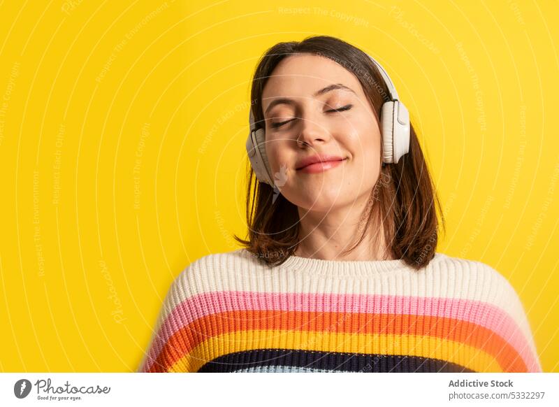 Lächelnde Frau mit Kopfhörern, die Musik hört zuhören meloman Glück positiv Gesang genießen Melodie Augen geschlossen Drahtlos lässig hell Stil jung Gerät