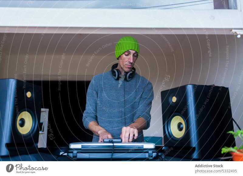 Mann spielt zu Hause am DJ-Mischpult dj Musik Konsole Mixer spielen Klang Gerät mischen Beanie heimwärts Audio Regler Schaltfläche unterhalten Aufzeichnen
