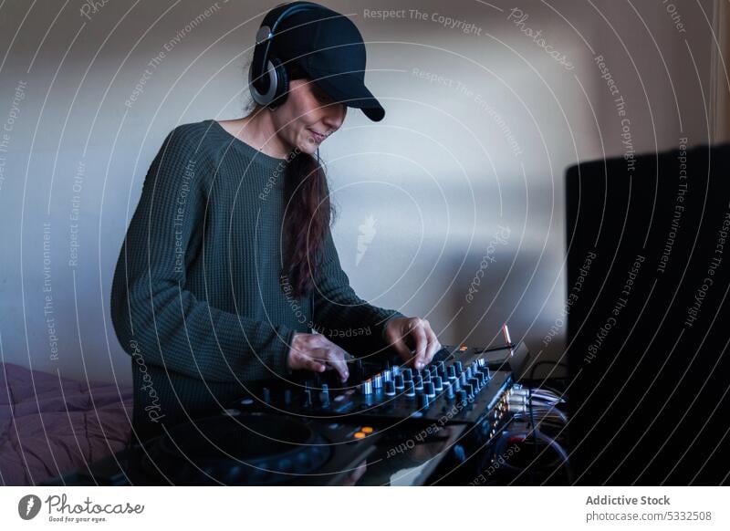 Weiblicher DJ mit Mischpult zu Hause Frau Lächeln Glück dj Konsole zuhören heimwärts Musik Atelier Regler Gerät Schaltfläche Erwachsener professionell Audio