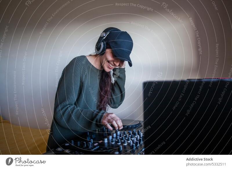 Weiblicher DJ mit Mischpult zu Hause Frau Lächeln Glück dj Konsole zuhören heimwärts Musik Atelier Regler Gerät Schaltfläche Erwachsener professionell Audio