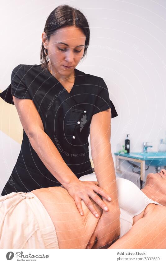 Fokussierte Masseurin massiert den Bauch des Kunden Frau Massage geduldig Spezialist Magen sich[Akk] entspannen Klinik Verfahren Schmerz medizinisch Therapie
