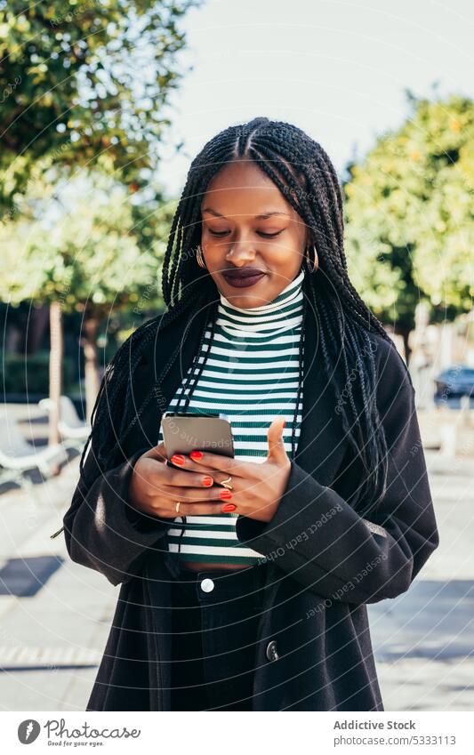 Schwarze Frau mit Smartphone auf der Straße benutzend Browsen Surfen Glück Nachricht Kommunizieren Großstadt Afroamerikaner Mobile ethnisch schwarz