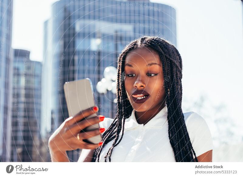 Schwarze Frau macht Selfie mit Smartphone benutzend Selbstportrait Straße Gerät Mobile Zunge Funktelefon fotografieren Großstadt Bank lässig Afroamerikaner