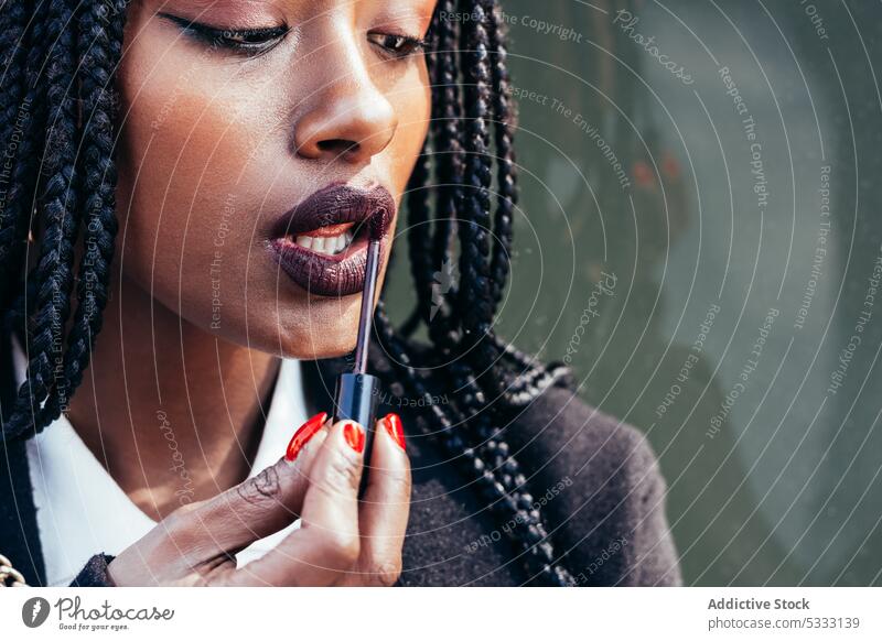 Schwarze Frau trägt auf der Straße Lippenstift auf bewerben Make-up benutzend Geflecht Gerät Mobile Gesicht Afroamerikaner ethnisch schwarz Afro-Look feminin