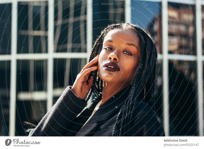 Afroamerikanische Frau mit Make-up auf der Straße Vorschein Rastalocken Porträt ernst starren Starrer Blick Model Afro-Zöpfe Stil jung schwarz Frisur stehen