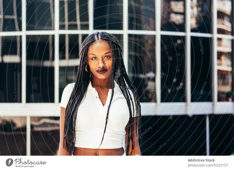 Schwarze Frau mit langen geflochtenen Haaren auf der Straße Geflecht Porträt starren urban trendy cool Starrer Blick emotionslos Individualität selbstsicher