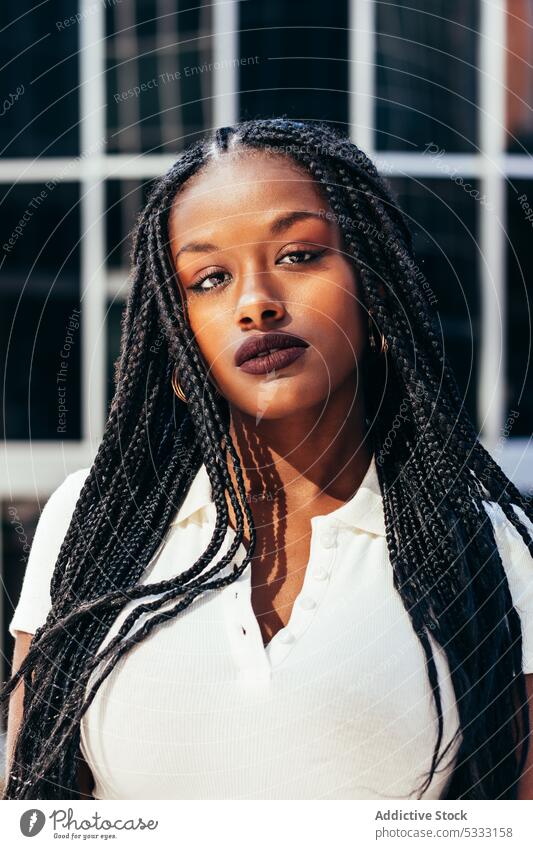Schwarze Frau mit langen geflochtenen Haaren auf der Straße Geflecht Porträt starren urban trendy cool Starrer Blick emotionslos Individualität selbstsicher