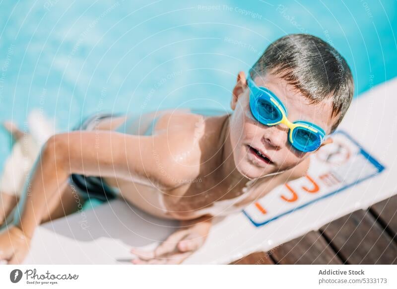 Lustiges Kind, das beim Verlassen des Schwimmbads in die Kamera schaut Junge schwimmen Pool Sommer Urlaub Beckenrand Feiertag genießen sich[Akk] entspannen