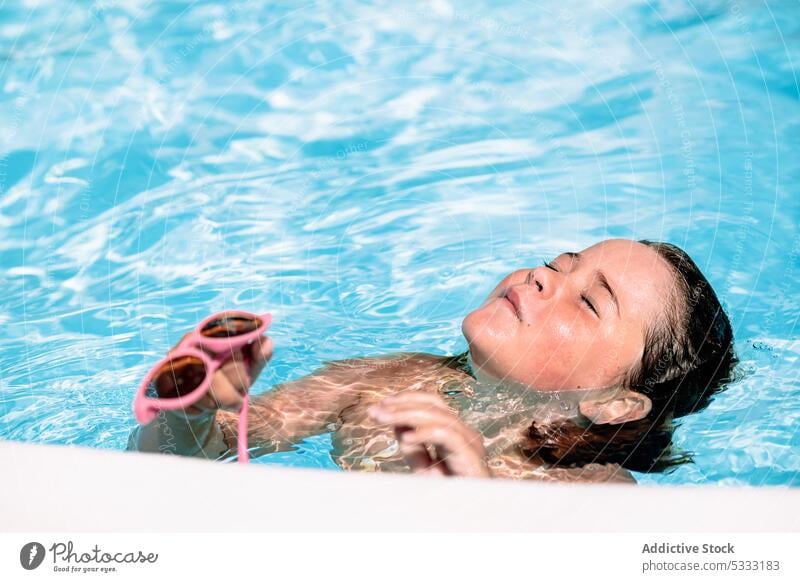 Glückliches Kind mit geschlossenen Augen beim Schwimmen im Pool Mädchen Sonnenbrille Halt schwimmen genießen Feiertag heiter Sommer Urlaub sich[Akk] entspannen