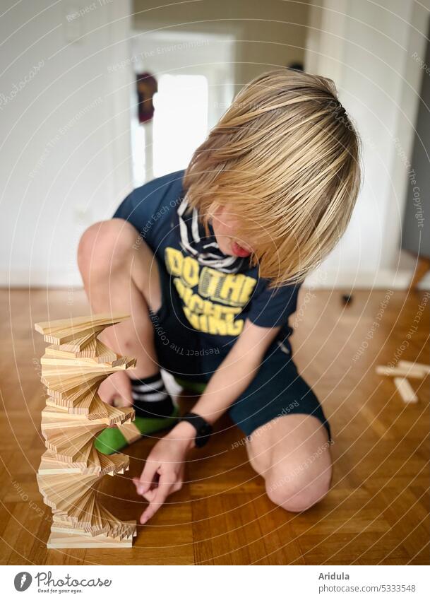Kind baut einen Holzturm auf dem Fußboden bauen spielen Junge Kindheit Spielzeug Baustein Bildung Konstruktion stapeln Wendeltreppe spiralförmig Wohnzimmer
