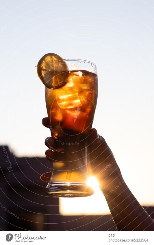 Dame mit einem kalten Glas Long Island Iced Tea-Cocktail bei Sonnenuntergang Alkohol - Getränk Bar - Getränkehandel Stadtleben Cola Erfrischungsgetränk
